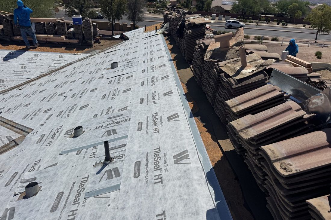 Tile roof lift-and-relay underway near Gilbert, Arizona, with new underlayment installed and the original tile stacked for re-laying